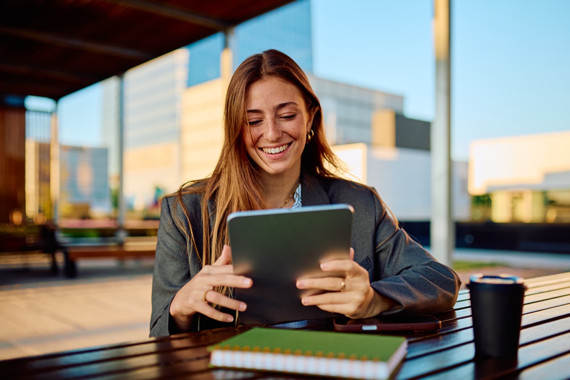 A smiling professional using a tablet outside a modern office